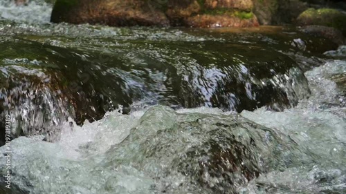 Closeup wild river flowing through rocks in the forest, Clear water stream rapid flows in tropical rainforest, Slow motion.