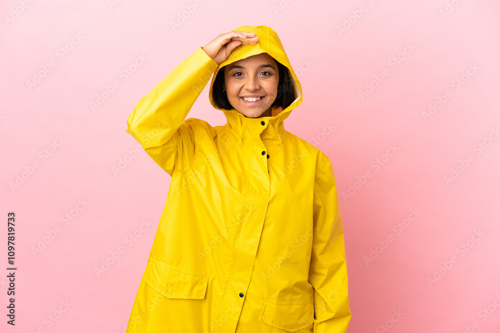 Young latin woman wearing a rainproof coat over isolated background saluting with hand with happy expression Young latin woman wearing a rainproof coat over isolated background saluting with hand with happy expression