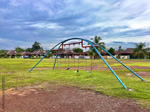A vibrant playground with swings, slides, and seesaws in a lush residential park, surrounded by shady trees and clean walking paths.