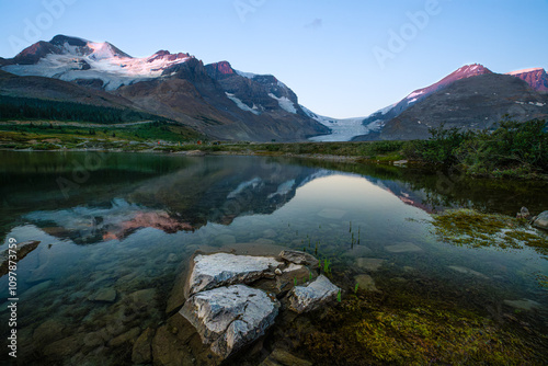 The panoramic view of snowy mountain and colorful clouds with lake reflections at ice field center of Jasper National Park. Famous Athabasca glacier in Canada at dawn. photo