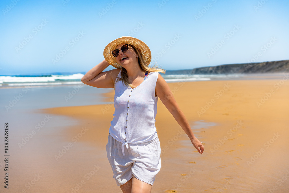 Beautiful mature woman tourist walking on sandy beach in summer. Bordeira praia, Portugal. Happiness and fun. Front view Beautiful mature woman tourist walking on sandy beach in summer. Bordeira praia, Portugal. Happiness and fun. Front view
