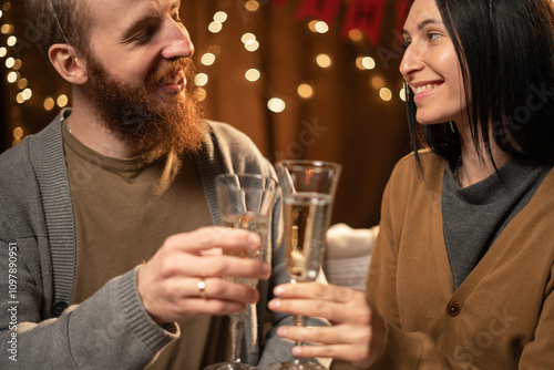 young couple drinking champagne and smiling while sitting face to face.