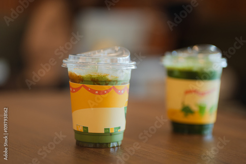 Close up and selcetive focus two glasses of iced matcha green tea on wooden table in cafe. photo