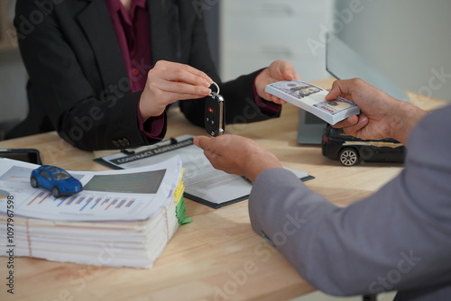 A salesperson introduces a customer sitting at a table with a small car and car keys. car dealer sales And the new owner has entered into a contract to sell close-up images. photo