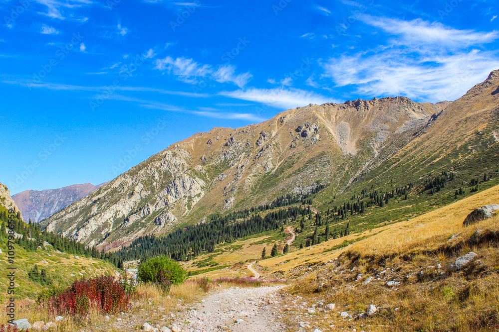 Snow-capped mountain peaks rising above golden autumn valley with winding river creating dramatic alpine landscape Snow-capped mountain peaks rising above golden autumn valley with winding river creating dramatic alpine landscape