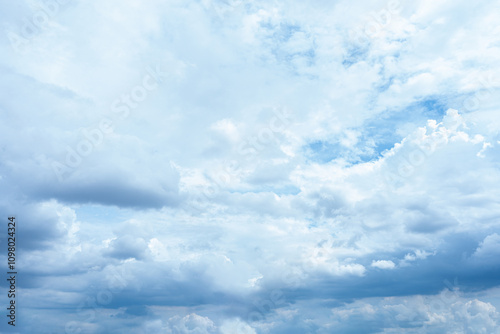 Fluffy white clouds drift across a bright blue summer sky