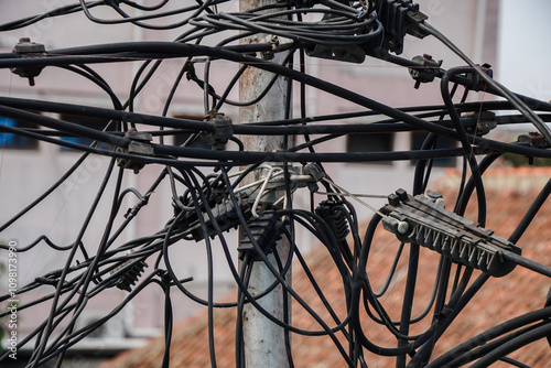 A close-up shot of a tangled mass of electrical wires on a utility pole. The scene is chaotic and complex. Tangled Electrical Wires on a Pole Background.