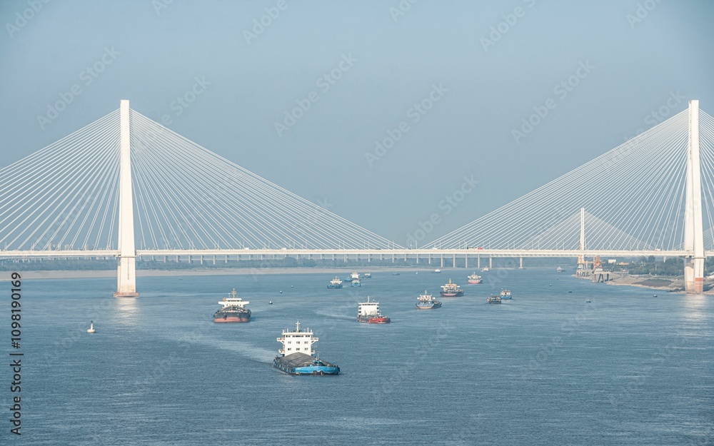 Fototapeta premium Cable-stayed bridge over river with cargo ships.