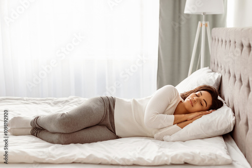 Full body length of calm young black woman sleeping well on the side. Beautiful African American lady resting, enjoying fresh cotton bedding, soft pillow and comfy mattress, banner, free copy space photo