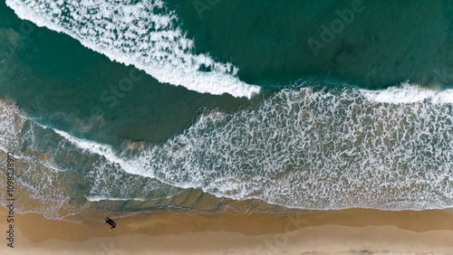 Aerial top-down view of sea waves crashing at sandy beach on sunny day, Puglia, Italy