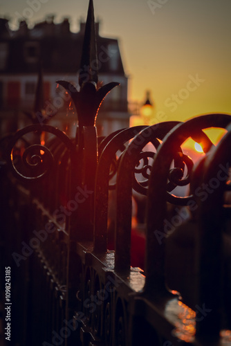 The rising sun penetrates with rays through the forged fence