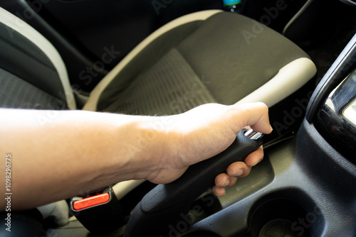 Close-up of a hand holding a car handbrake lever with chrome accents, focusing on grip and control.. photo