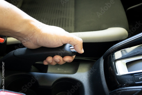 Close-up of a hand holding a car handbrake lever with chrome accents, focusing on grip and control.. photo