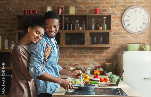 Loving black wife and husband preparing dinner. Happy family cooking vegetarian food in loft kitchen photo