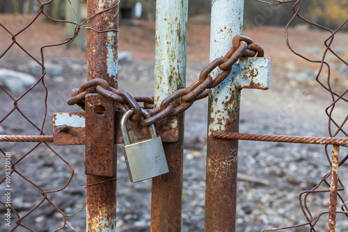 The metal gate is locked with a chain and has a padlock.