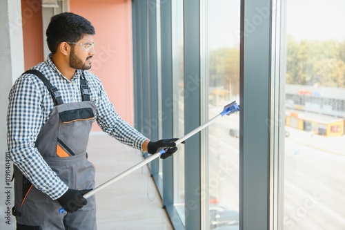 Male professional cleaning service worker cleans the windows and shop windows of a store with special equipment photo