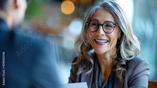 Fototapeta Naklejka Na Ścianę i Meble -  Smiling mature business woman hr holding cv document at job interview. Happy mid aged professional banking manager or lawyer consulting client sitting at workplace in corporate office meeting.