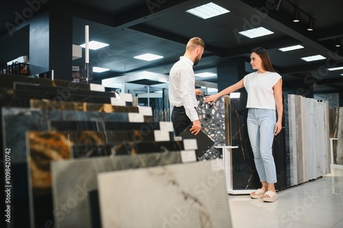 Salesman and a female customer choosing a right ceramic tile for her home, at the home design store