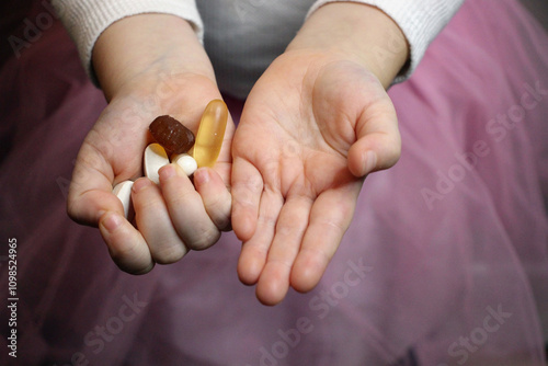 Child holding various pills and supplements in palms.
