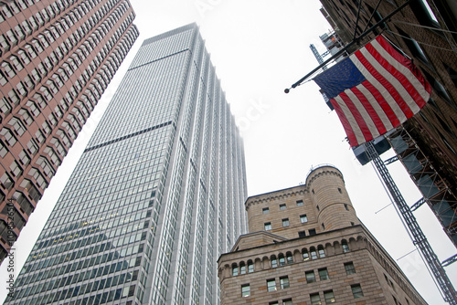 flag of USA on the facade of a building with skyscrapers around. cloudy winter day