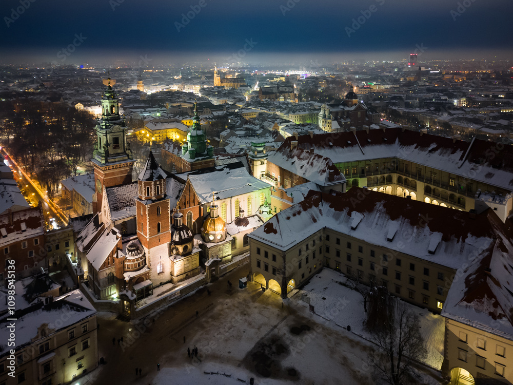 Naklejka premium Aerial view of snowy Wawel castle and Wawel cathedral from a drone on a cold winter night
