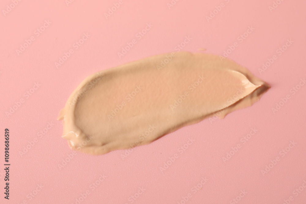 Fototapeta premium Sample of foundation on pink background, top view