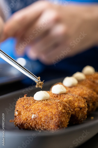 Chef decora croquetas deliciosas con trufa negra en un restaurante elegante para una cena exquisita en vajilla de porcelana gris con alcachofas en tempura e iluminación natural photo
