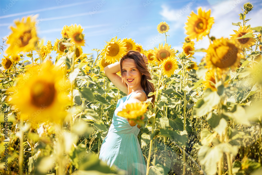 A woman in a light blue dress stands in a vibrant sunflower field under ...