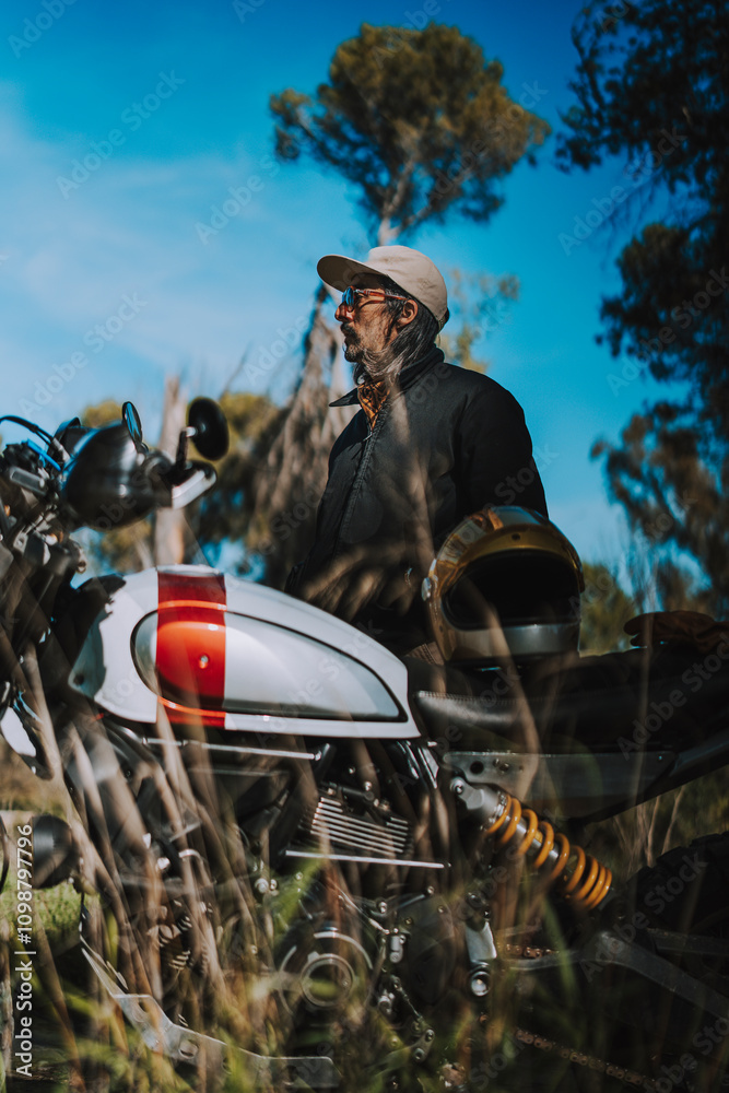 Hombre con barba y estilo alternativo con moto de campo en paso de bosque