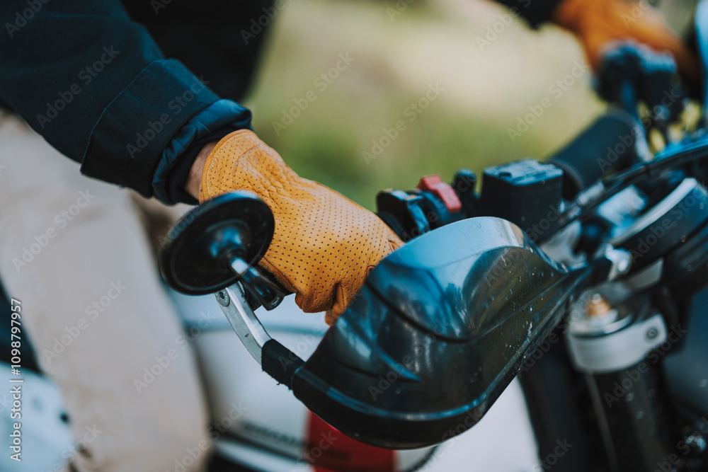Foto detalle de mano con guante amarillo de cuero en manillar de moto de campo