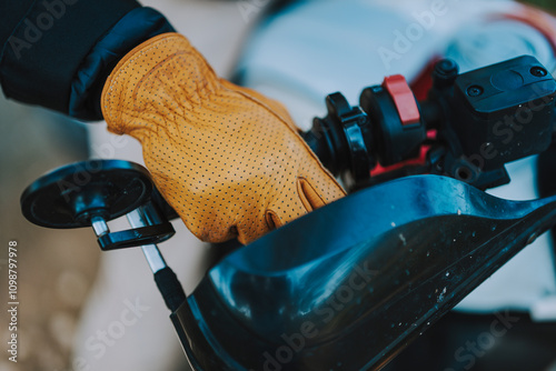 Obraz na płótnie Foto detalle de mano con guante amarillo de cuero en manillar de moto de campo w salonie