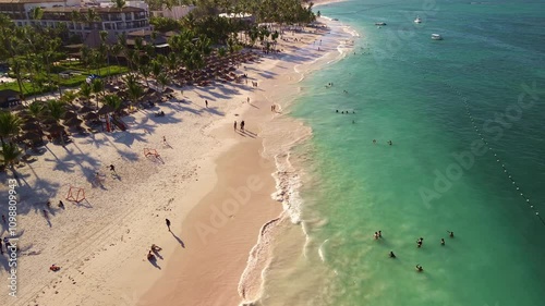 Aerial view of the snow-white tropical beach of the luxury hotel.Vacationers swim in the turquoise ocean water and sunbathe.Parked tourist catamarans for outdoor activities,romantic dates on vacation