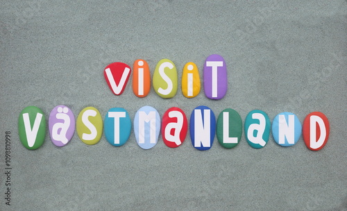 Visit Vastmanland, a county or ln in central Sweden, souvenir composed with multi colored hand painted stone letters over green sand photo