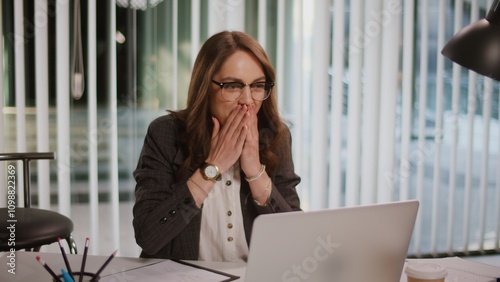 Cheerful Young Businesswoman in a Modern Office Working on a Laptop Concept of Productivity Positive Work Environment and Professional Success. Vibrant Office Atmosphere, Creativity, and Collaboration