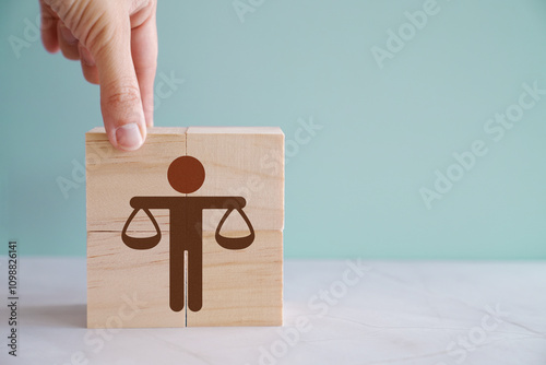 Hand holding Human justice scale on wooden block , business ethics and corporate compliance concept
