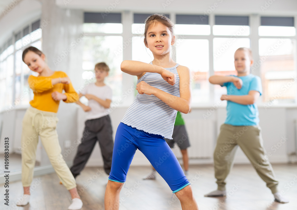 Fototapeta premium Girl learns to dance hip hop during childrens master class in studio. Teacher watches students, participates in training
