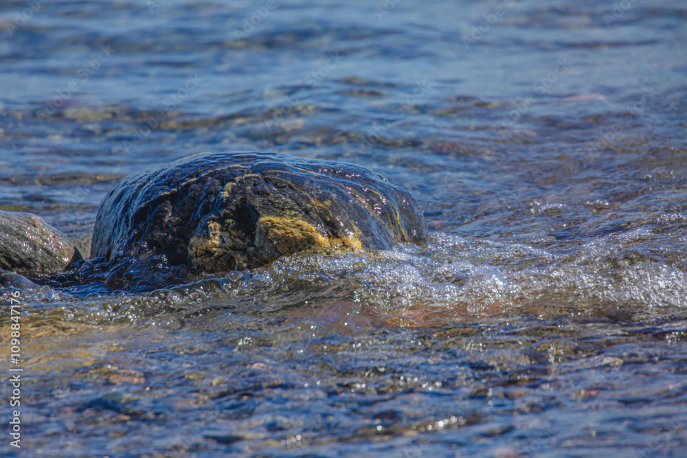 Fototapeta premium Waves Washing Over A Rock In the Lake