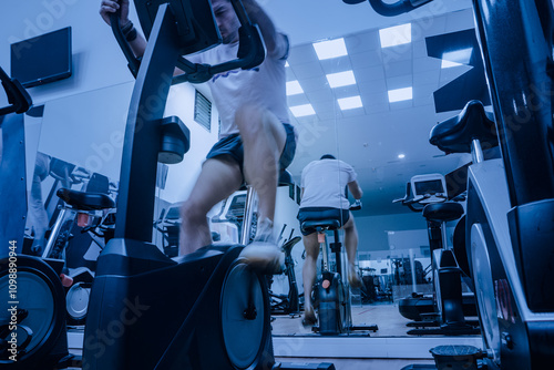 Deportista entrenando en gimnasio sobre bicicleta elíptica. photo