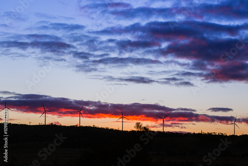 silhouetted wind turbines power generators on ridgeline at dusk after sunset photo