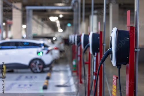 Obraz na płótnie EV charger and electric car, Electric car charger station for charge ev battery, Plug for vehicle with electric engine, EV charger clean energy, Charging point at car parking lot department store. w salonie