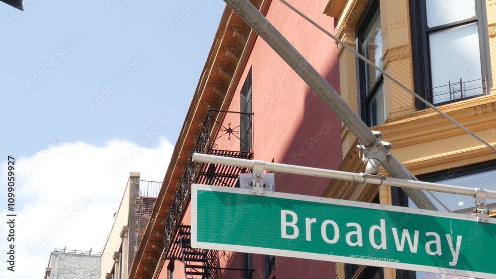Naklejka premium Broadway street road sign, Manhattan midtown property, house architecture, New York City real estate. Green roadsign on crossroad. Historic district intersection, United States.
