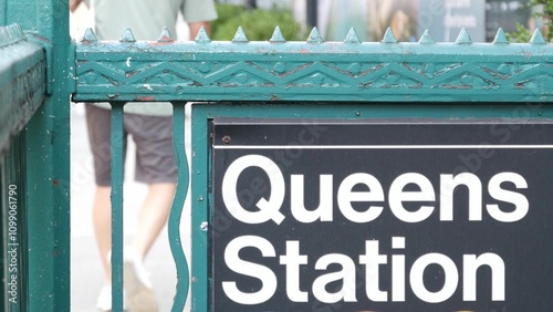 New York subway sign, Queens underground metro station. Metropolitan entrance fence, public transport exit. Long Island city street, NYC United States. Navigation text on signboard. Pedestrians people