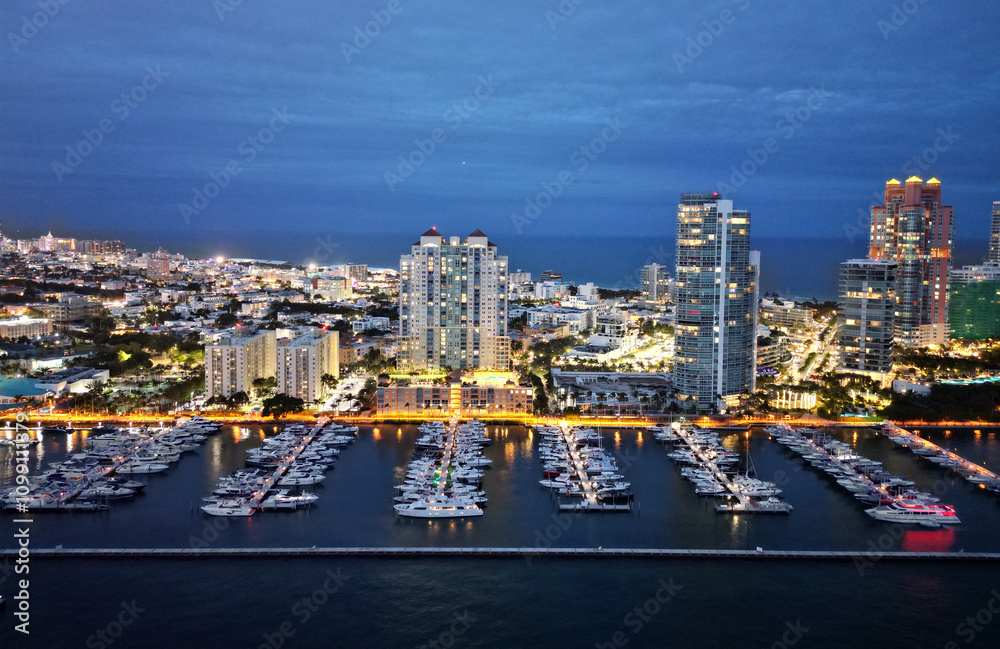 Naklejka premium Summer vacation. Luxury South beach marina. Luxury yacht at night. Miami south beach view. Yacht club. Marina in night Miami. Downtown Miami marina with luxury illuminated yacht. Docked vessels