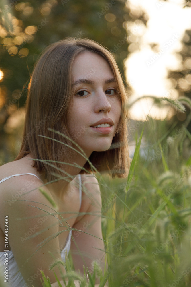 Naklejka premium This is a captivating portrait of a young woman, beautifully captured in a sunlit field
