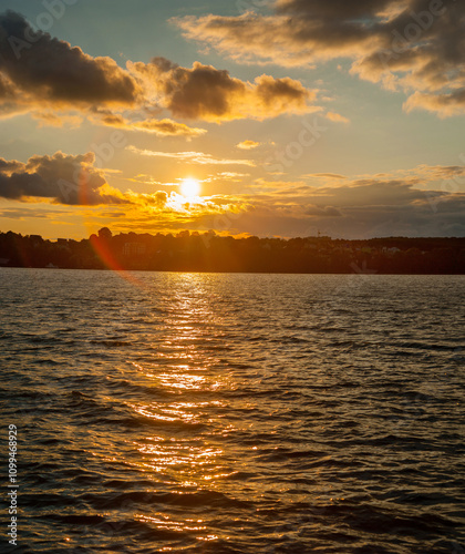 evening landscape on the lake sunset, waves and beautiful clouds illuminated ...
