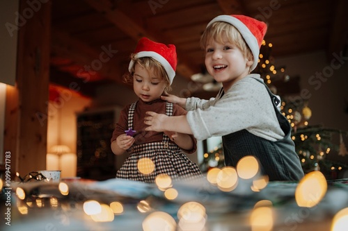 Siblings making holiday Christmas cards for family. Children painting pictures for Santa Claus or making christmas decorations with tempera paints. photo