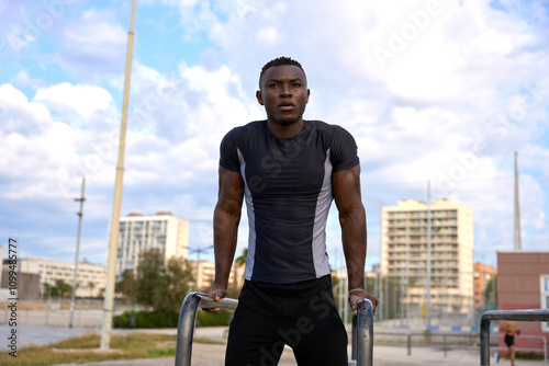 Young black man performing calisthenics exercises outdoors in urban setting