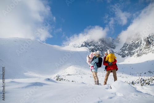 Young family is enjoying winter holiday in the mountains, standing in the middle of snowy landscape. photo