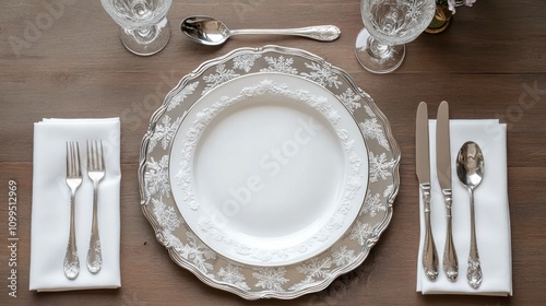 Silver-themed place setting with snowflake dinner plates, white napkins, and shiny metallic utensils photo