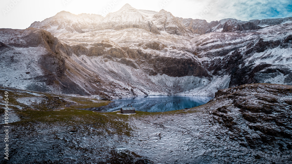 Naklejka premium Winter Majesty of the Ibón de los Asnos in Panticosa, Aragon: Frozen Waters and Snowy Mountains in the Heart of the Pyrenees Captured from a Drone. 